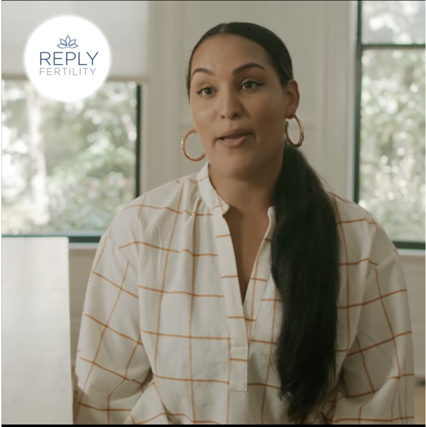 A woman wearing hoop earrings and a plaid shirt says reply fertility