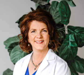 A woman in a white lab coat is smiling for the camera.