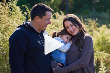 A man and a woman are holding a baby in their arms.