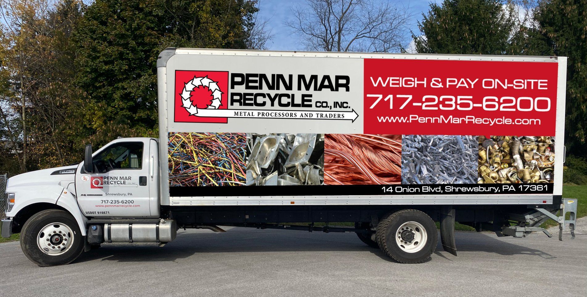 A white Penn Mar Recycle box truck parked outdoors, featuring company logo, contact info, and photos of scrap metal.