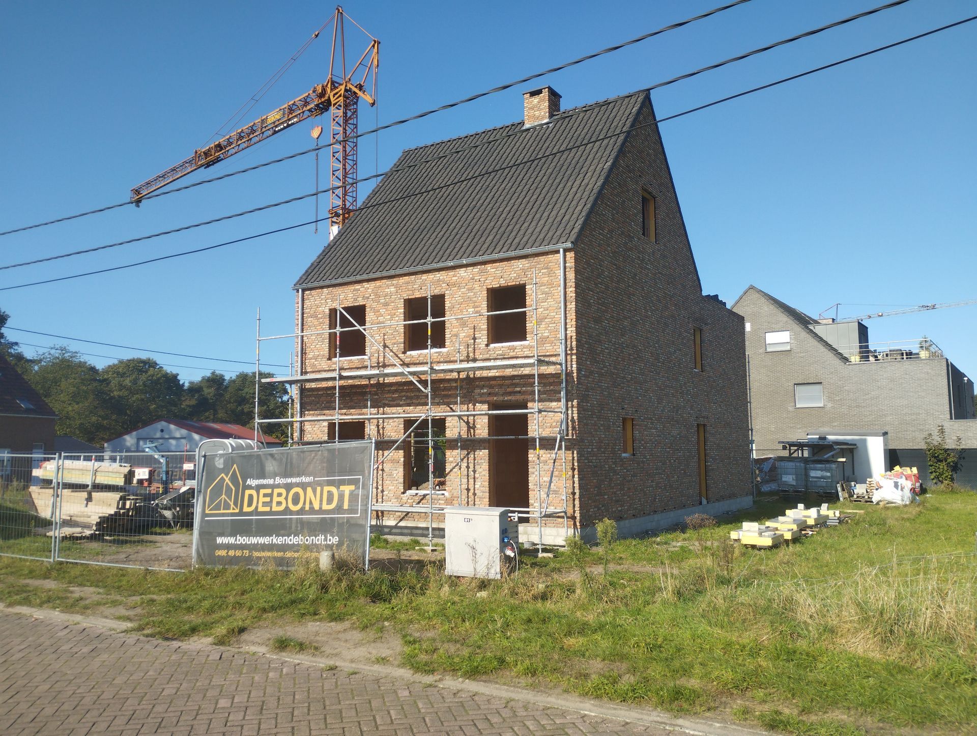 Bakstenen huis met donkergrijs dak, oprit aan de voorzijde en garage in een buitenwijk.