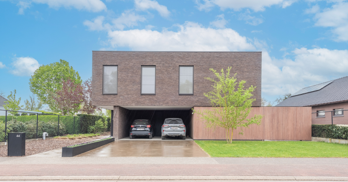 Bakstenen huis met donkergrijs dak, oprit aan de voorzijde en garage in een buitenwijk.