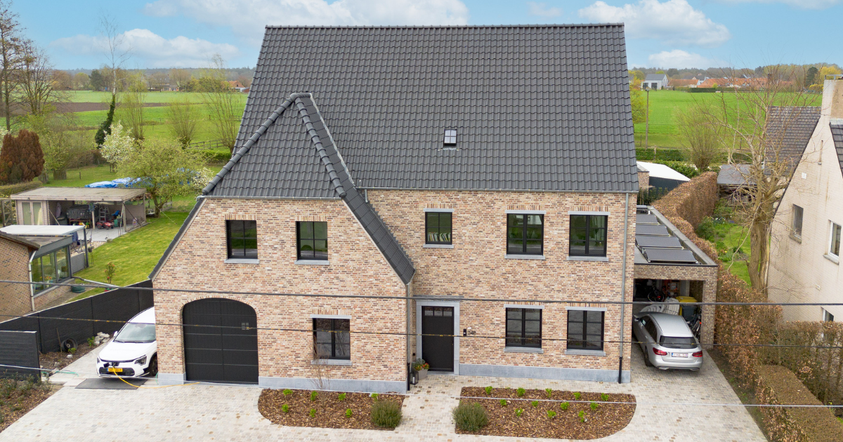 Bakstenen huis met donkergrijs dak, oprit aan de voorzijde en garage in een buitenwijk.