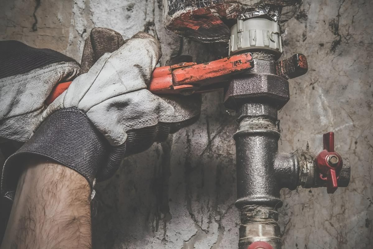 Man is Fixing a Pipe With a Wrench — Wet & Dry Plumbing & Gas in Newtown, QLD