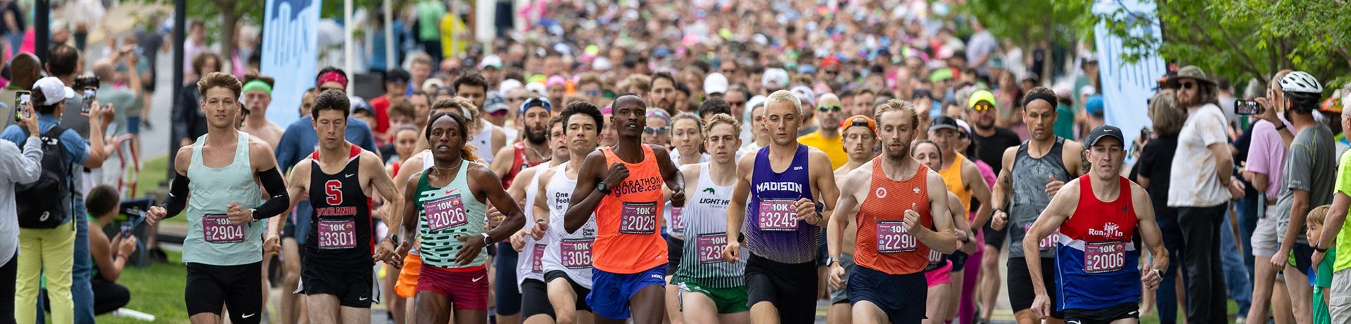 A large group of runners starting a race on an asphalt road; spectators lining the sides.