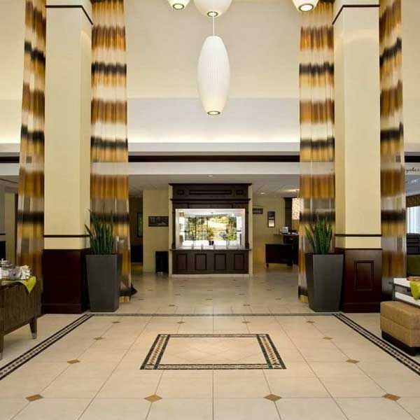 Hotel lobby with pillars, reception desk, and tiled floor.