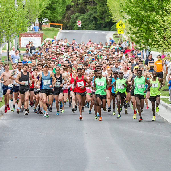 A large group of runners starting a race on an asphalt road; spectators lining the sides.