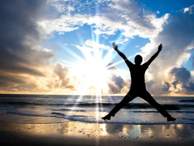 person jumping for joy at an ocean sunset to demonstrate the joy recovery from addiction to pornography