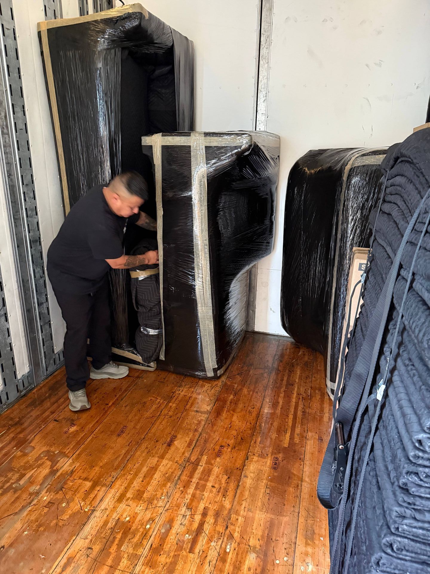 A man is moving a piano into a moving truck.