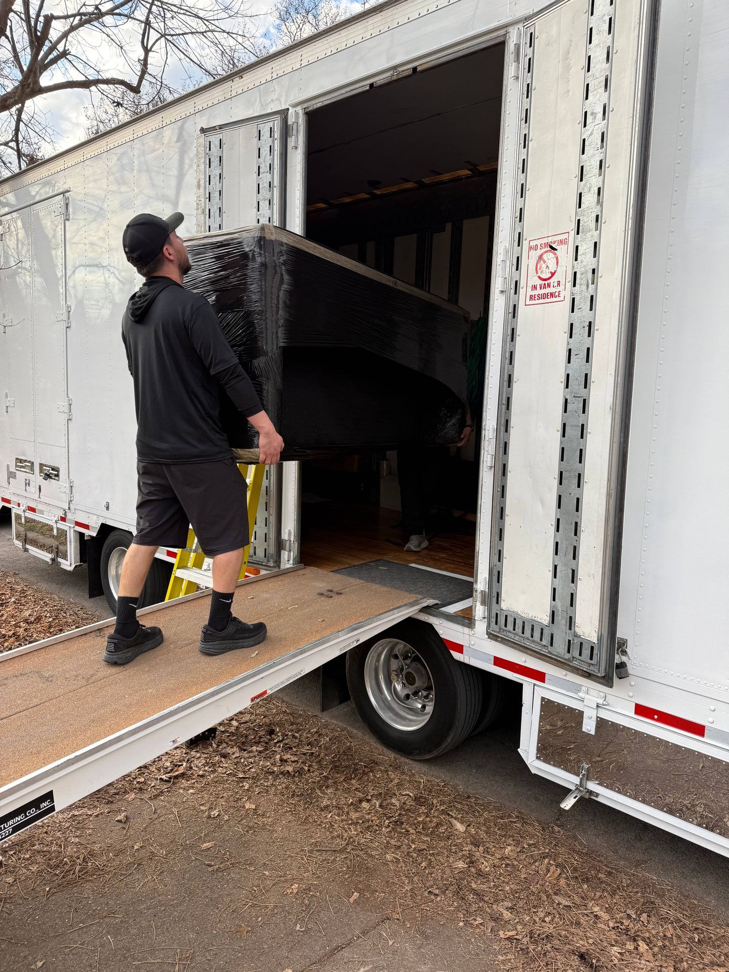 A man is loading a piano into a moving truck.