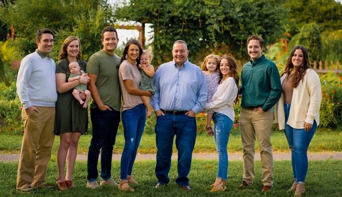 A large family is posing for a picture together in a park.