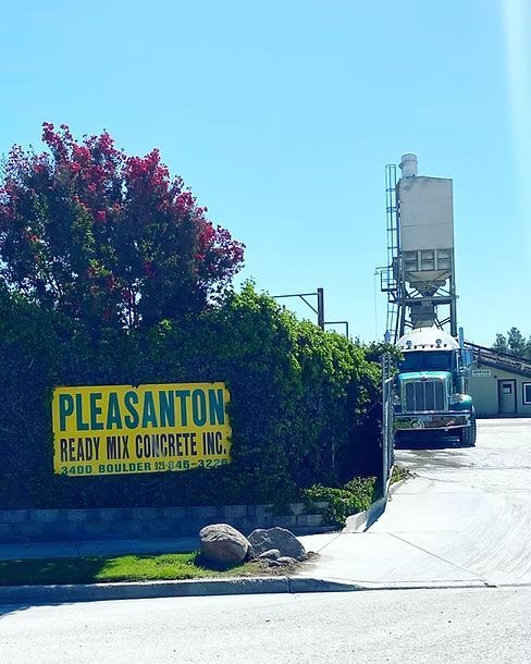 Pleasanton Ready Mix Concrete sign by a driveway with a concrete truck and silo Pleasanton Ready Mix Concrete sign by a driveway with a concrete truck and silo