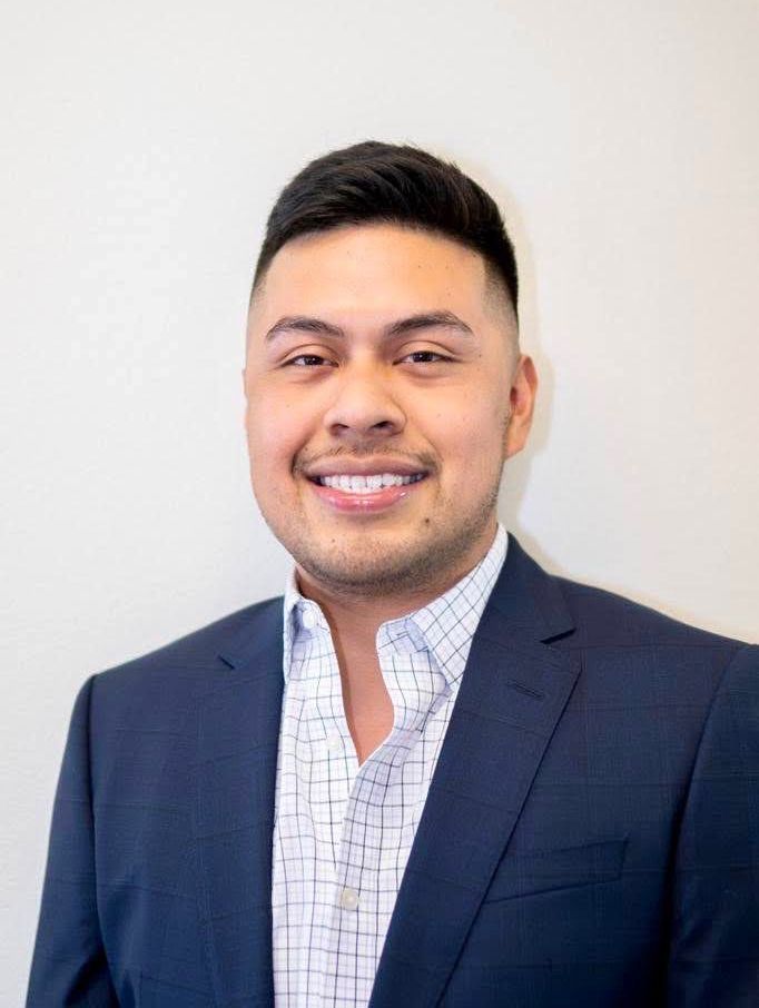 A man in a suit and plaid shirt is smiling for the camera.