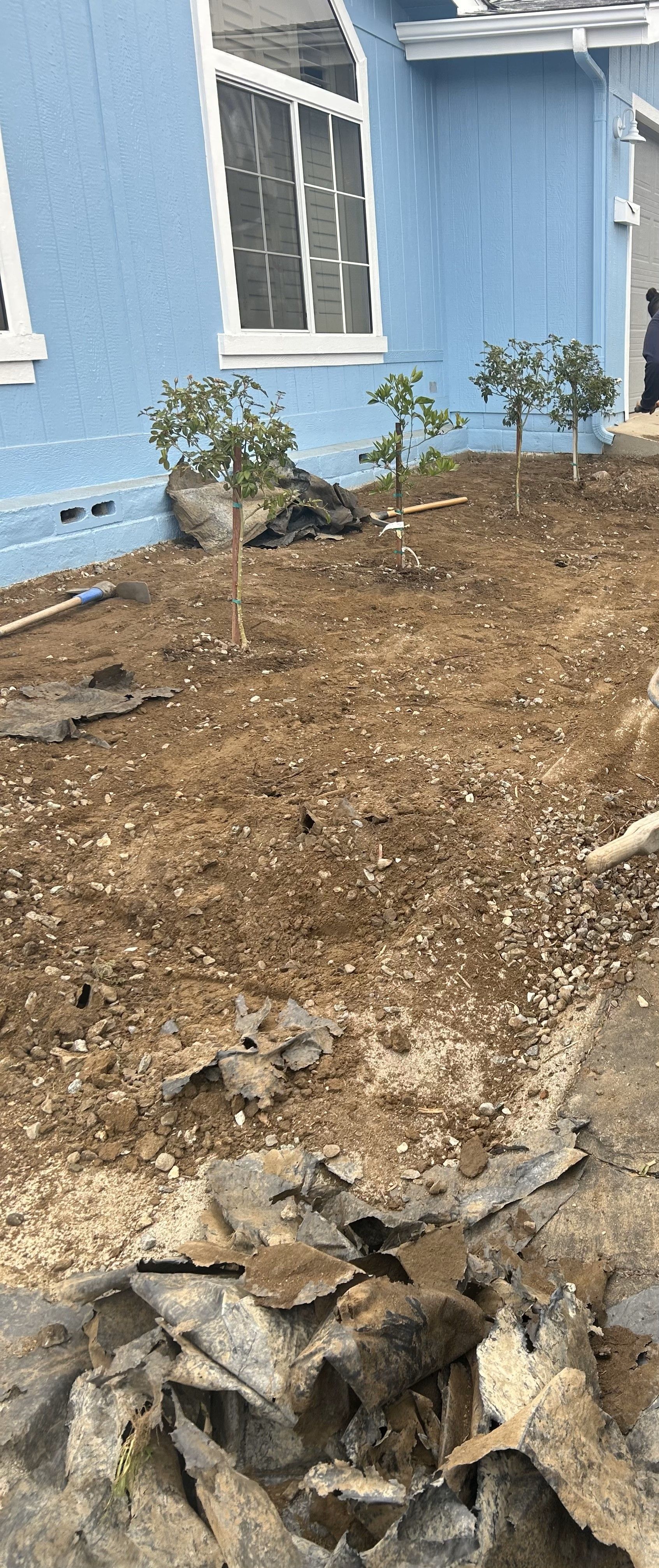 A blue house with a lot of dirt in front of it.