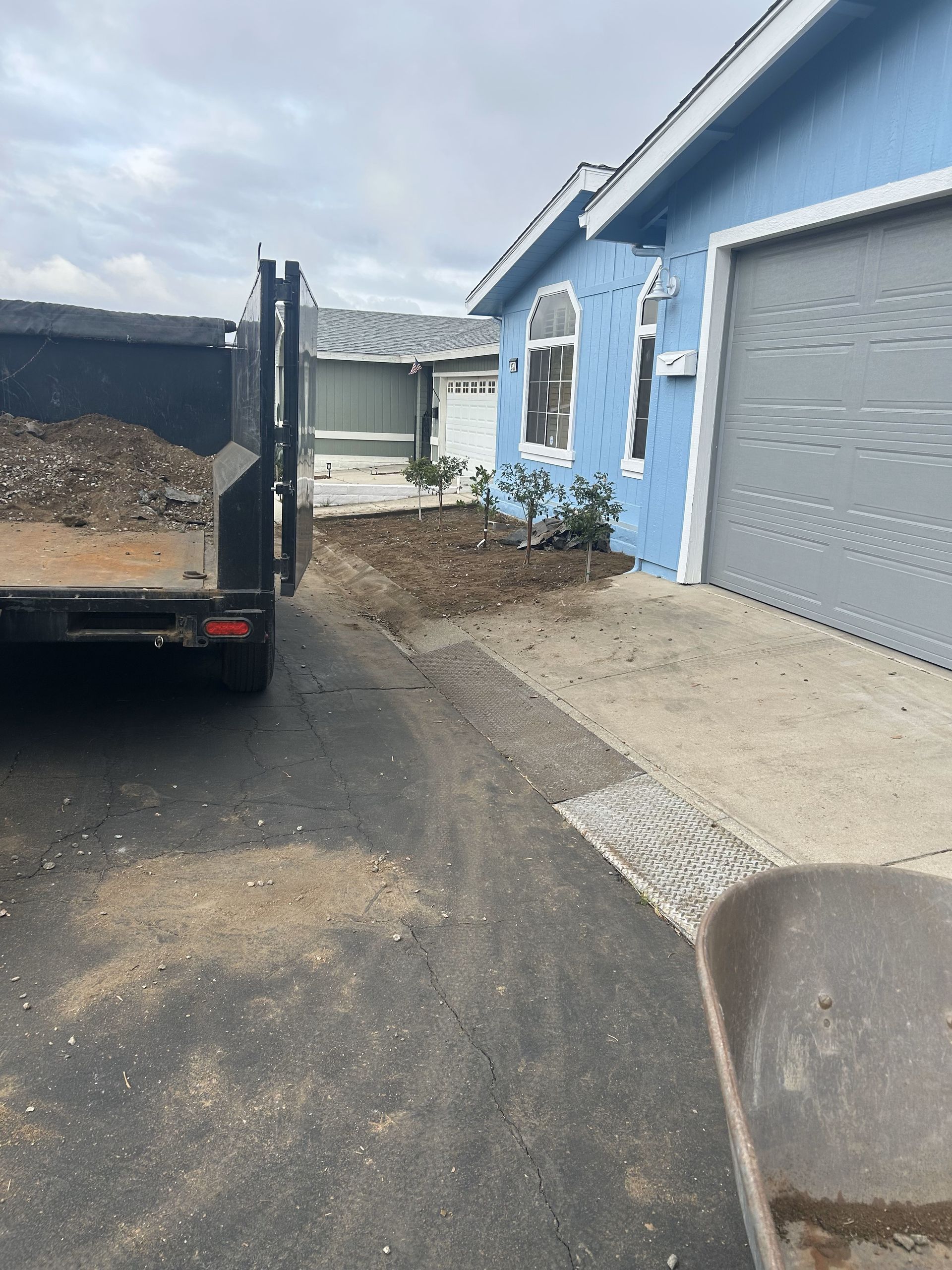 A dump truck is parked in front of a blue house.