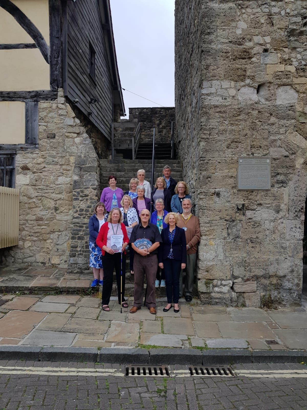 A group of people are posing for a picture in front of a stone wall.