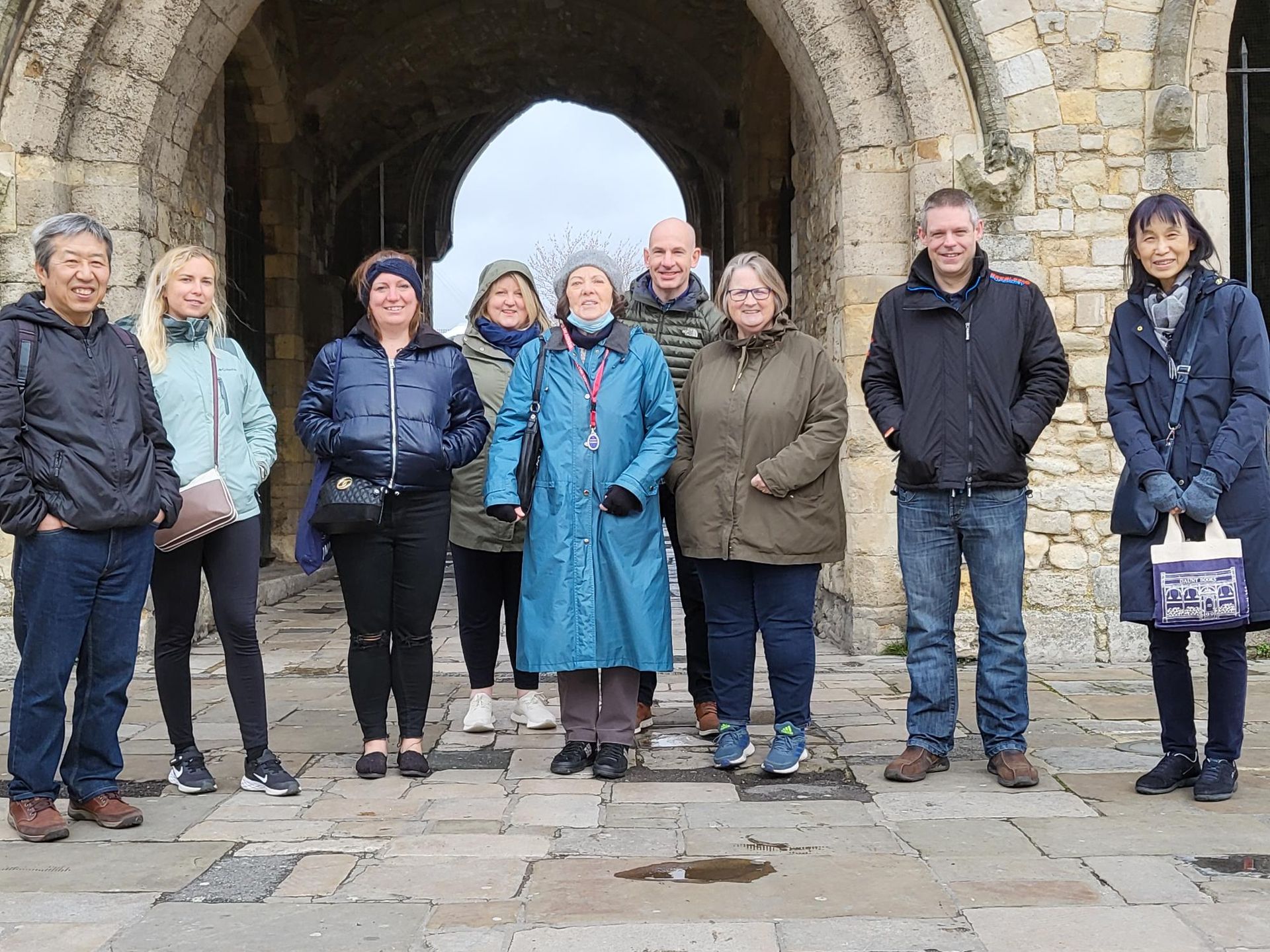 A group of people are standing in front of a stone archway.