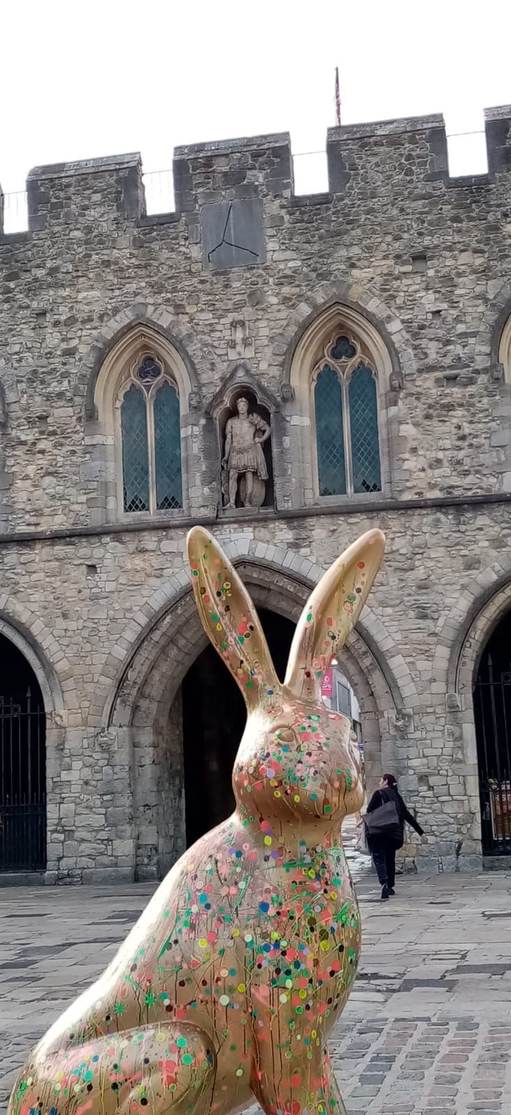 A statue of a rabbit is sitting in front of a stone building.