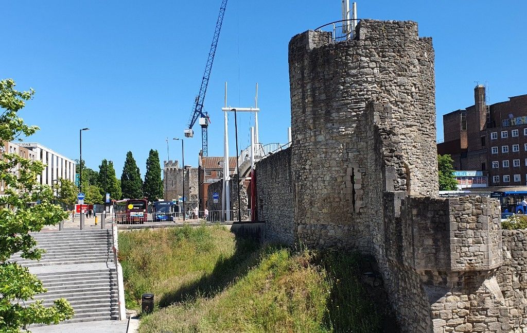 A large stone tower is sitting on top of a hill in the middle of a city.