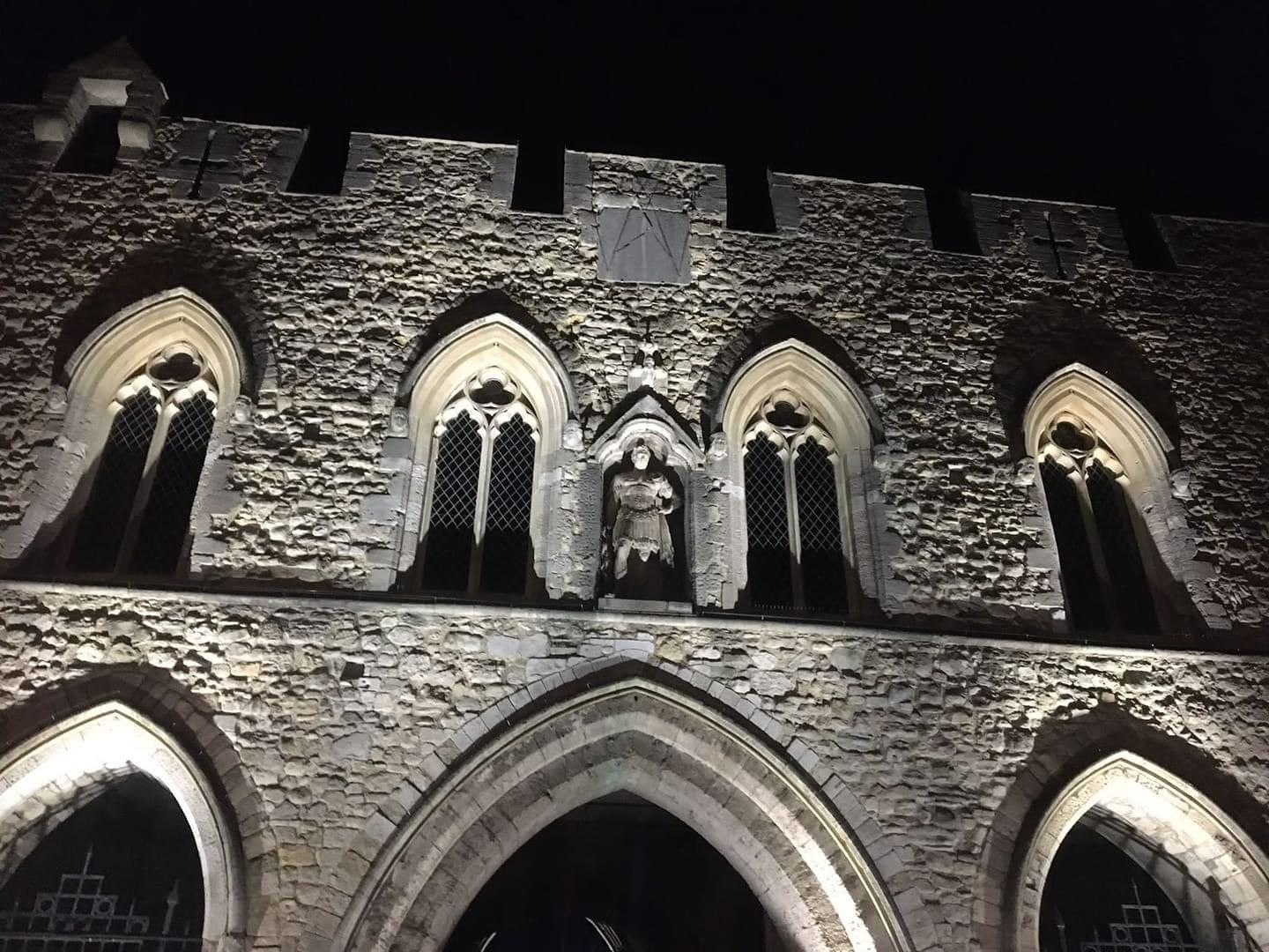 A brick building with arches and windows is lit up at night