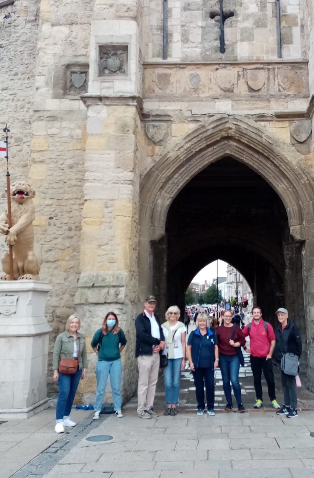 A group of people are standing in front of a stone archway.