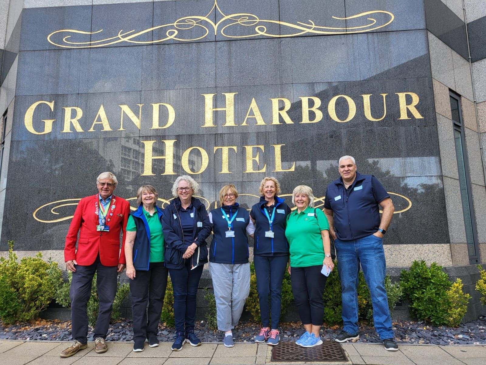 A group of people standing in front of a sign that says grand harbour hotel