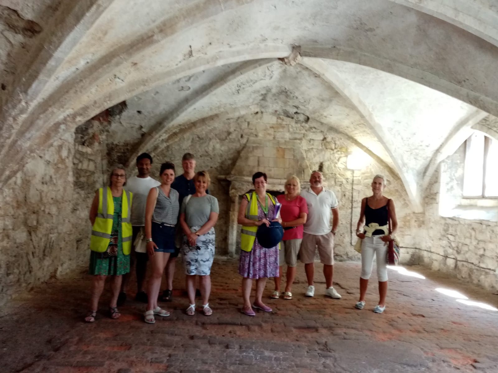 A group of people are standing in a room with arched ceilings.