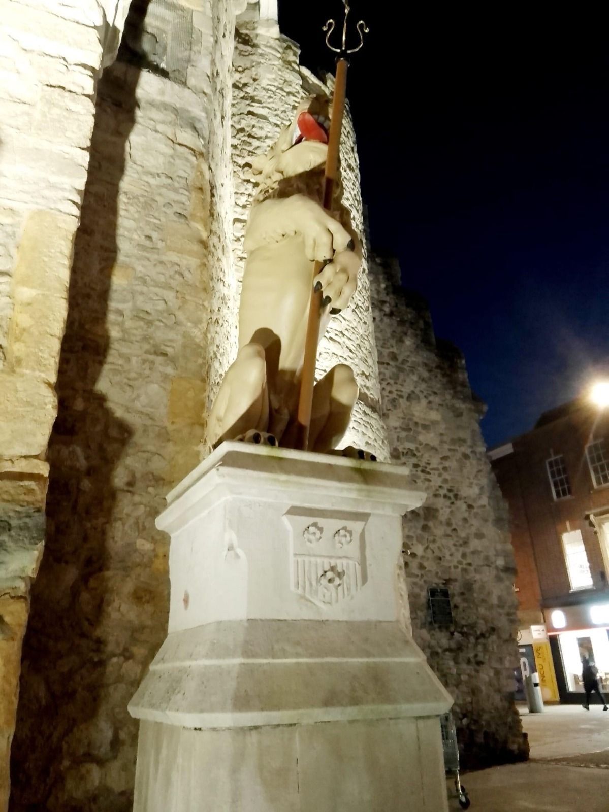 A statue of a man holding a trident in front of a stone wall