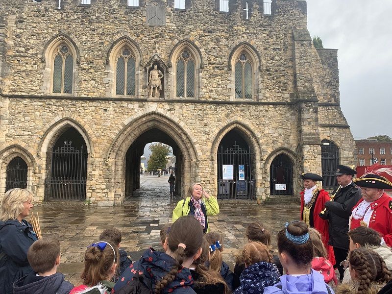 A group of people are standing in front of a stone building.