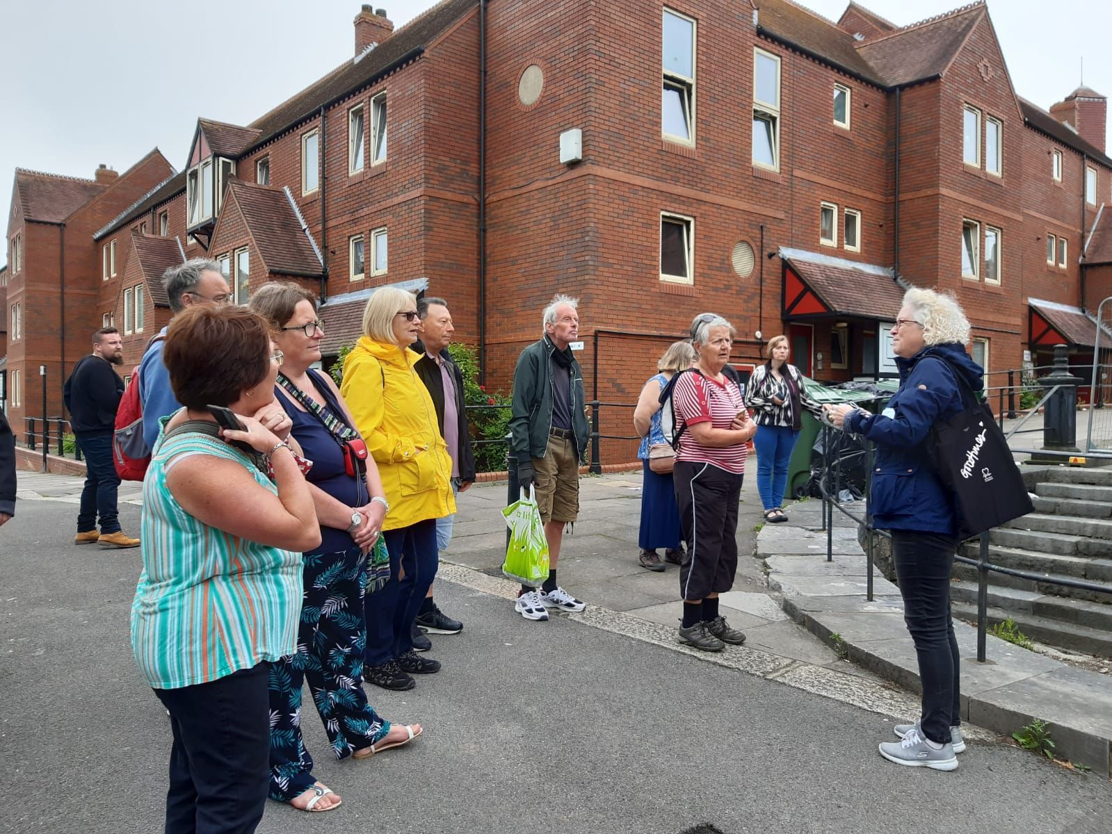 A group of people are standing in front of a brick building.
