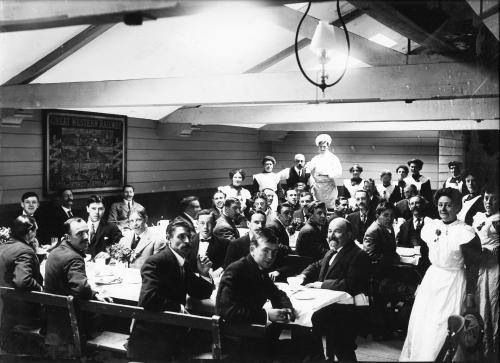 A black and white photo of a group of people sitting at tables