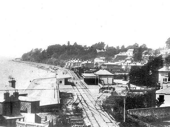 A black and white photo of a train station near the water