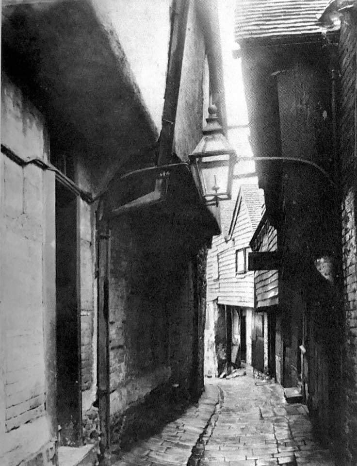 A black and white photo of a narrow alleyway between two buildings