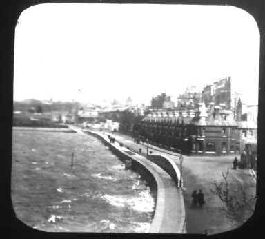 A black and white photo of a city along a body of water.
