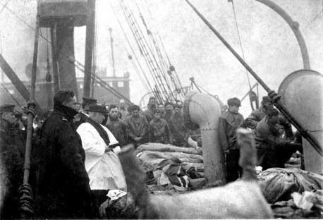 A black and white photo of a group of people on a ship.