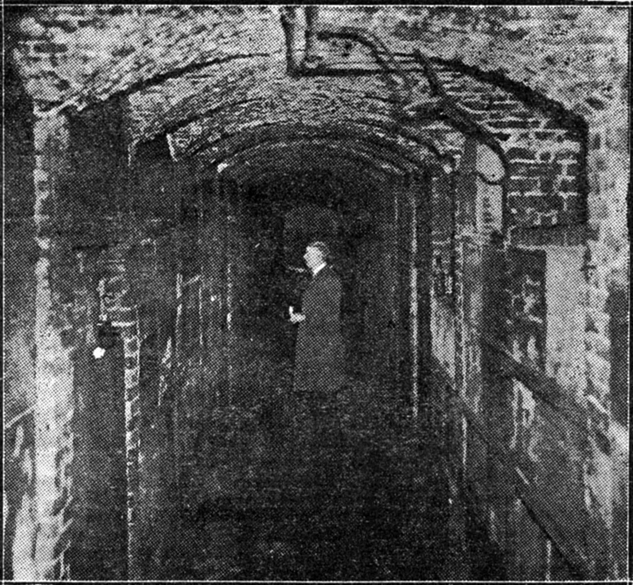 A black and white photo of a man standing in a tunnel.