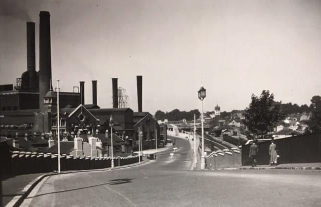 A black and white photo of a factory with smoke stacks