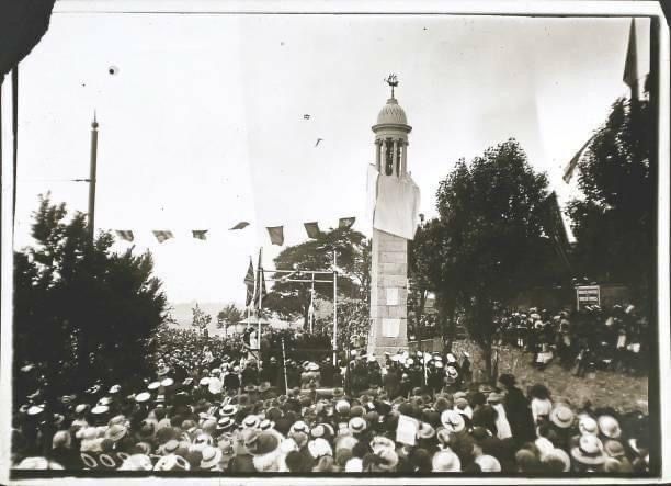 A black and white photo of a crowd gathered in front of a clock tower