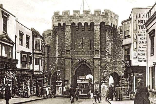 A black and white photo of a city street with a castle in the background.