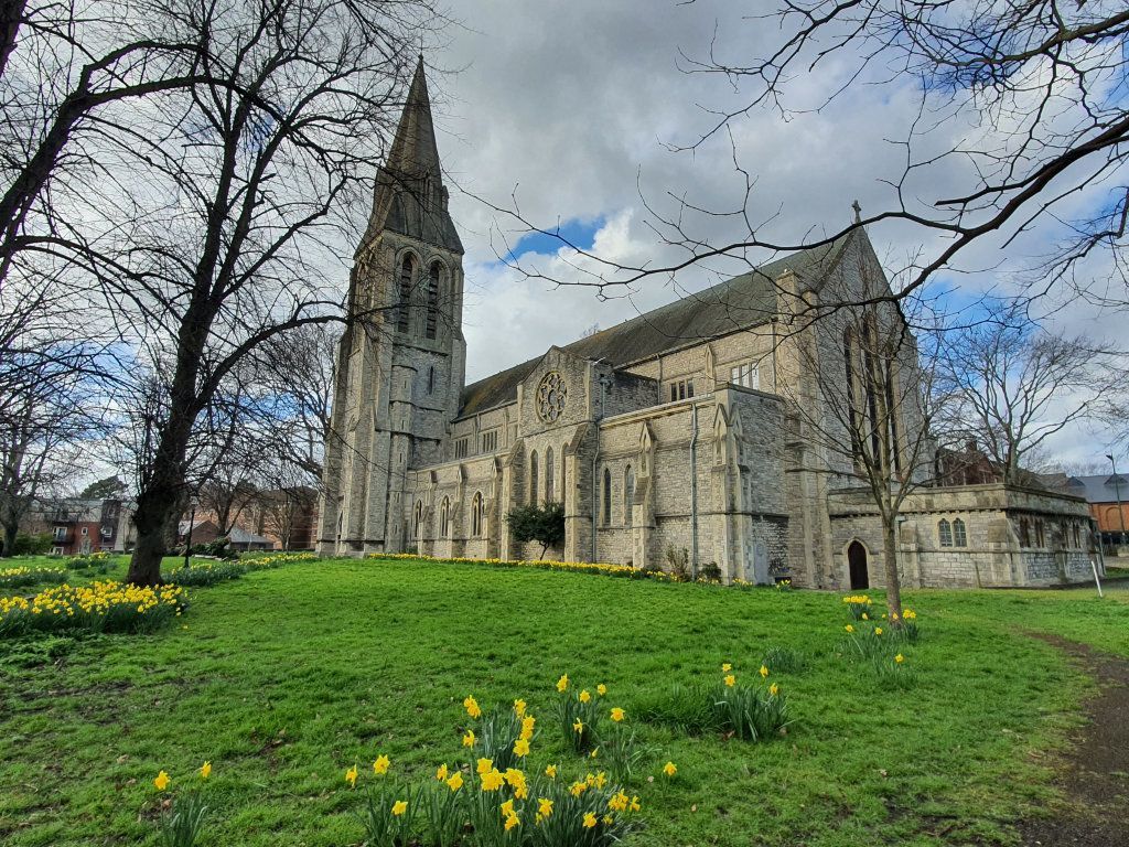 A large stone church with a steeple and a blue sky in the background