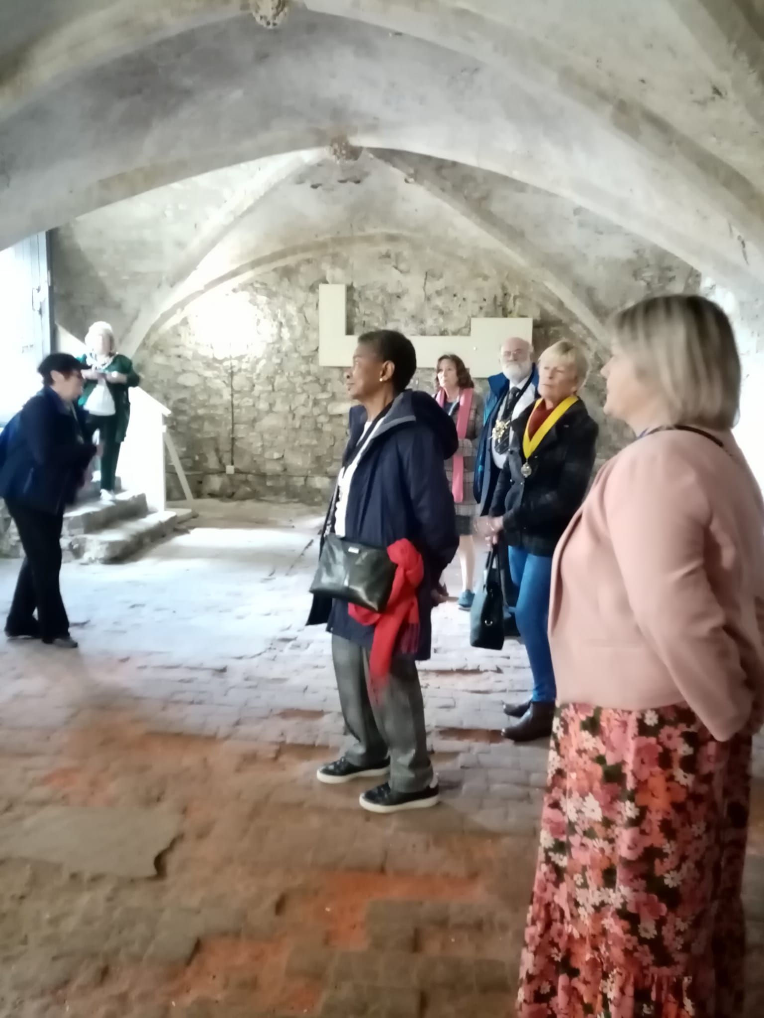 A group of people are standing in a room with a vaulted ceiling.