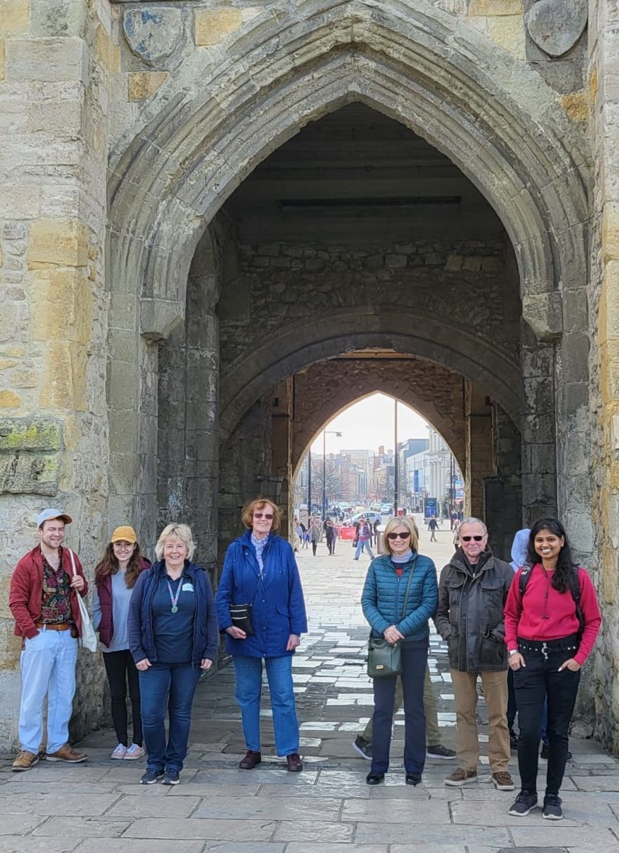 A group of people are standing in front of a stone archway.