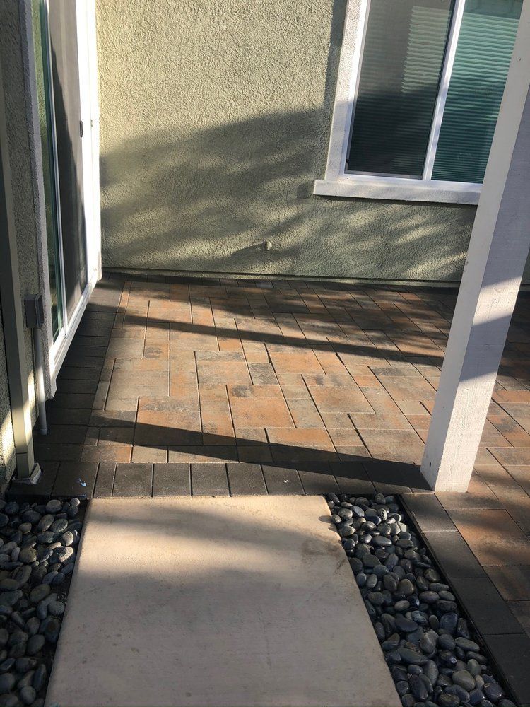 A brick walkway leading to a house with a window.
