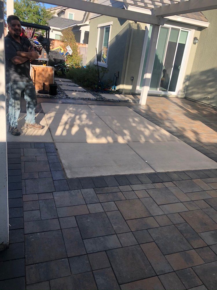 A man is standing on a patio under a pergola.