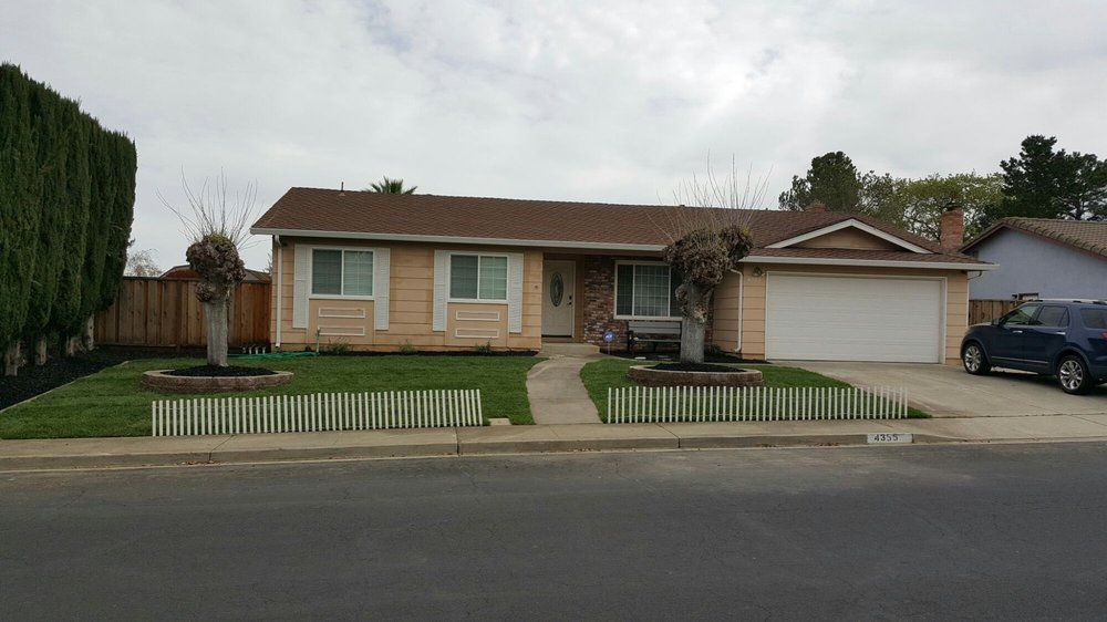 A house with a car parked in front of it on a cloudy day.