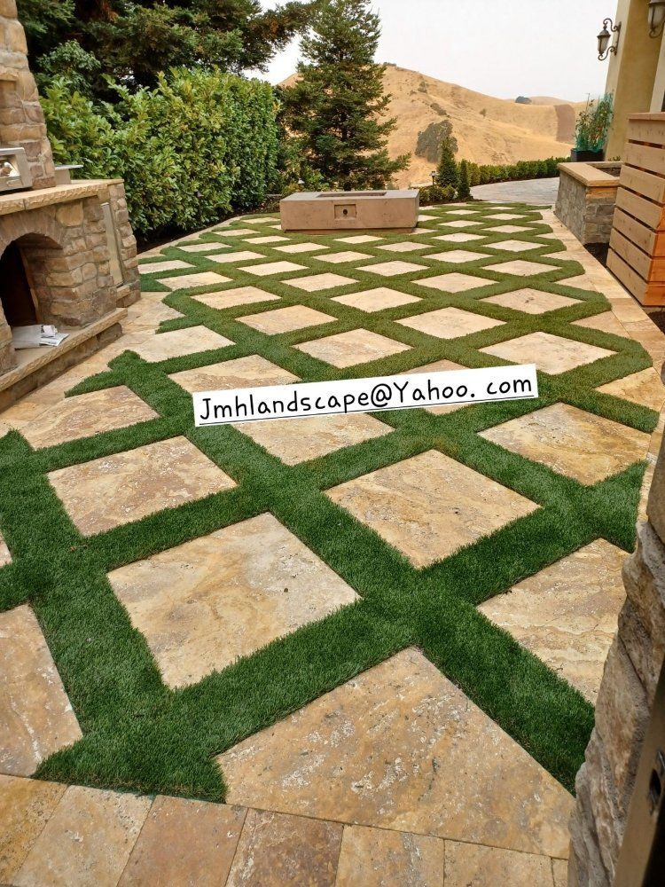 A patio with a lot of grass and a fireplace.