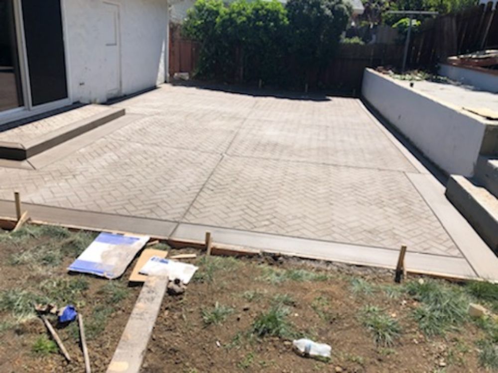 A concrete driveway is being built in the backyard of a house