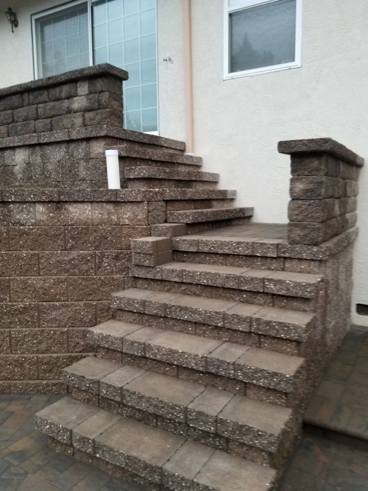 A set of stairs leading up to a house with a brick wall behind them.