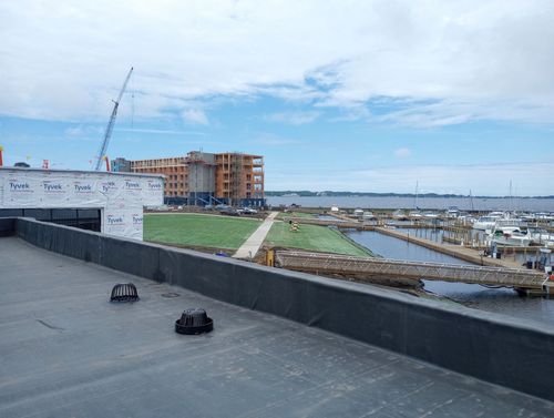 Rooftop view of a waterfront marina with boats, a canal, and buildings under a cloudy sky
