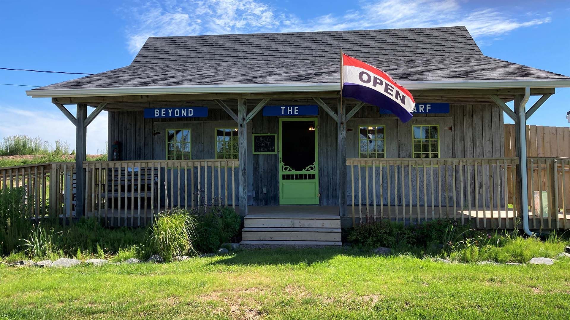 a small cute building with a coverd porch and an open flag waving in the wind. Beyond the warf artisans